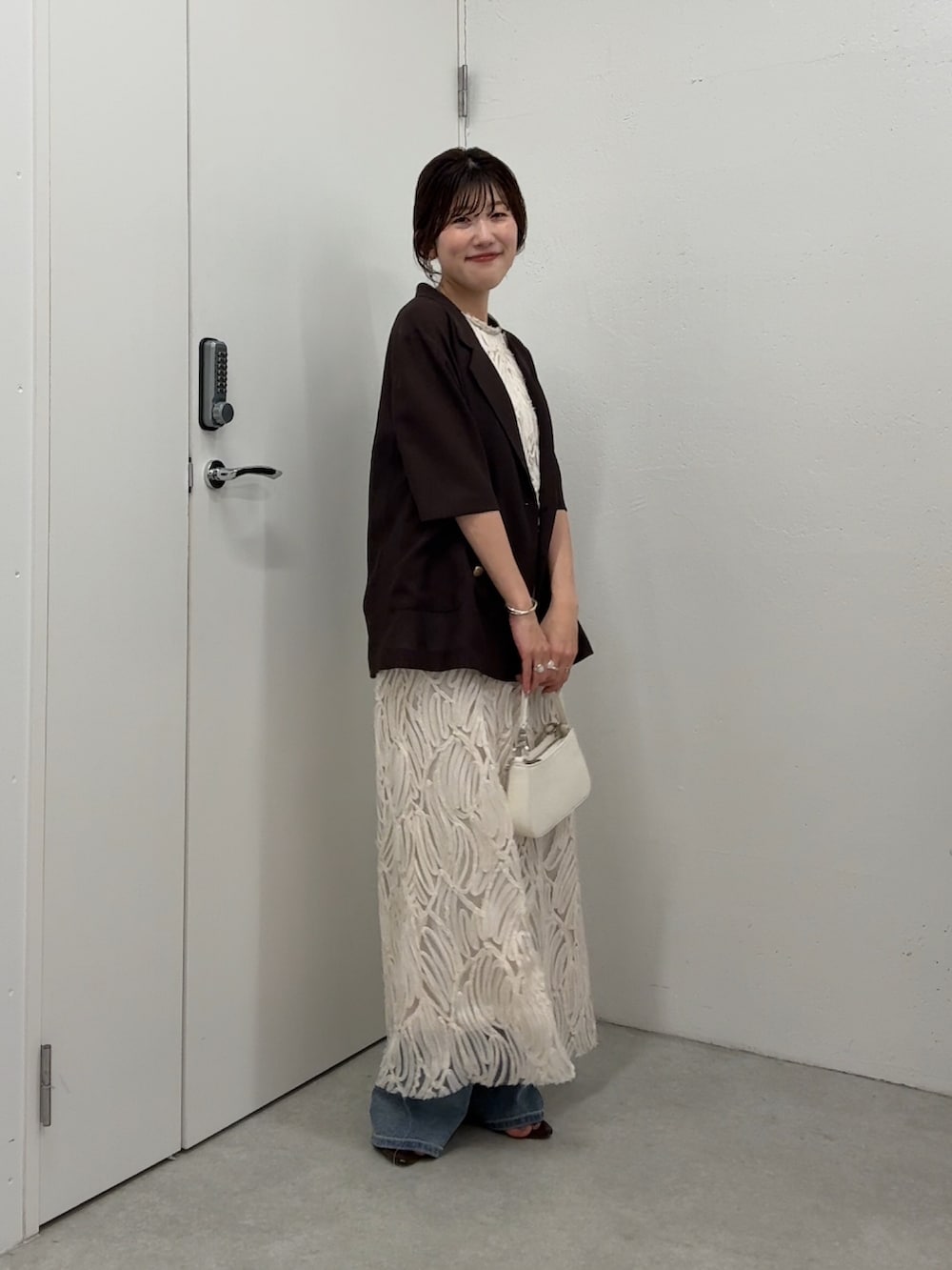 ホワイト系のワンピース、ブラウン系のテーラードジャケット、ホワイト系のショルダーバッグを着用したレディースの春コーディネートの2枚目の写真