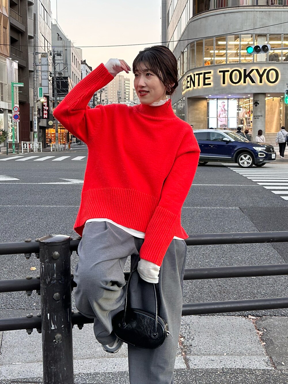 オレンジ系のニット/セーター、グレー系のスラックス、ホワイト系のTシャツ/カットソーを着用したレディースの冬コーディネートの3枚目の写真