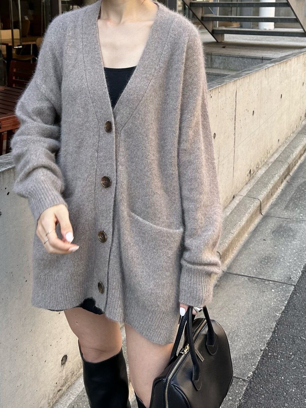 ブラウン系のカーディガン/ボレロ、ブラック系のボストンバッグ、ブラック系のブーツを着用したレディースの冬コーディネートの2枚目の写真