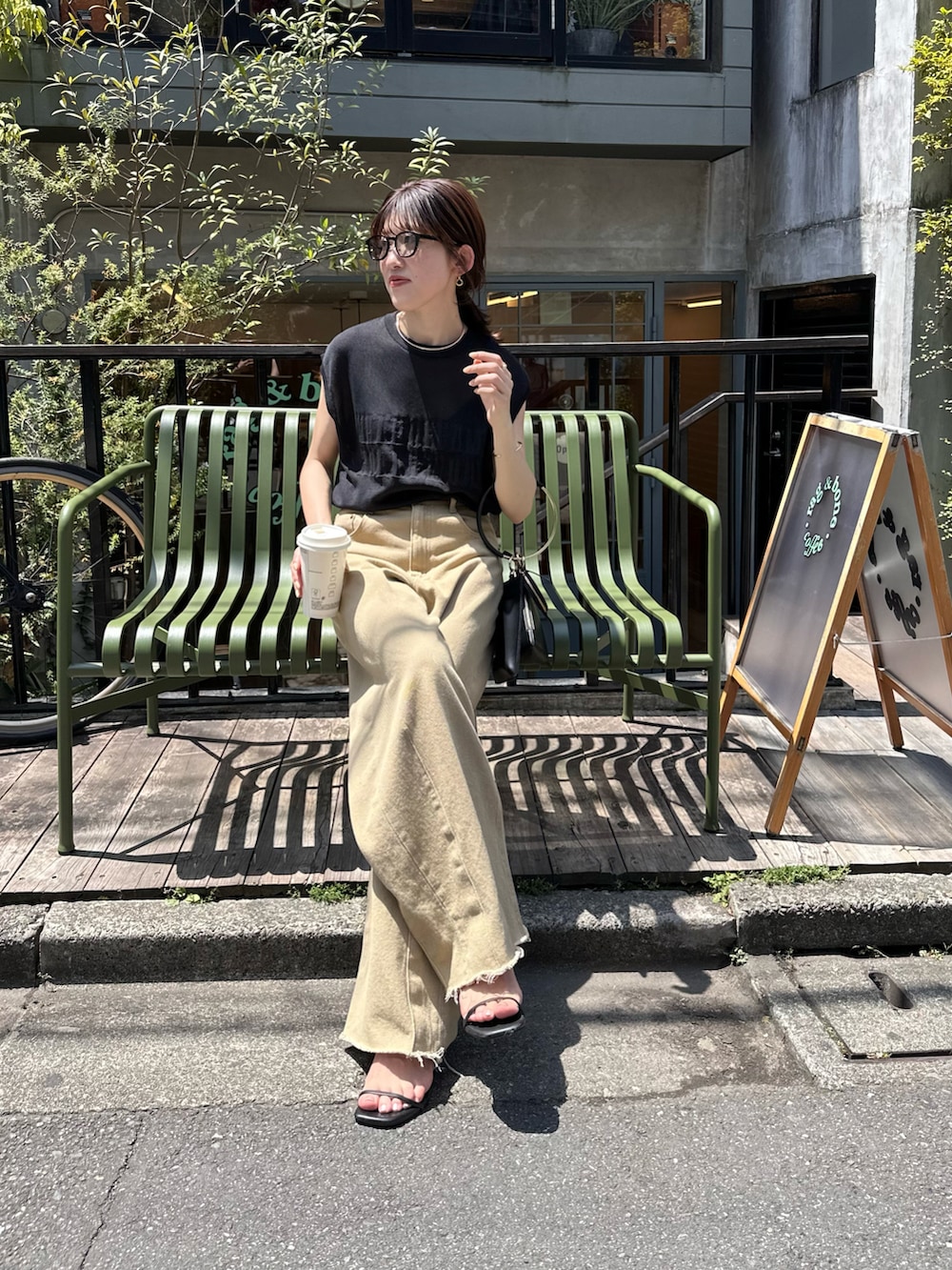 ブラック系のニット/セーター、ホワイト系のバッグ、ベージュ系のデニムパンツを着用したレディースの春コーディネートの4枚目の写真