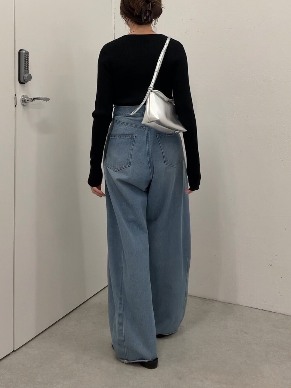 ブラック系のニット/セーター、ブルー系のデニムパンツ、シルバー系のショルダーバッグを着用したレディースの夏コーディネートの2枚目の写真