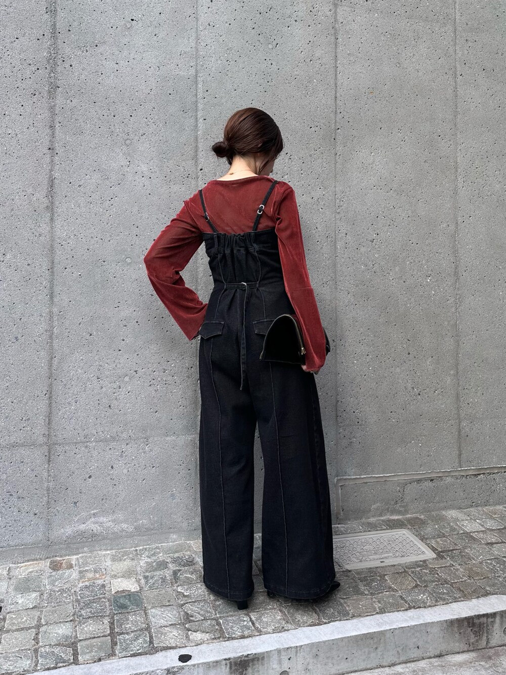 レッド系のTシャツ/カットソー、ブラック系のサロペット/オーバーオール、ブラック系のブーツを着用したレディースの秋コーディネートの3枚目の写真