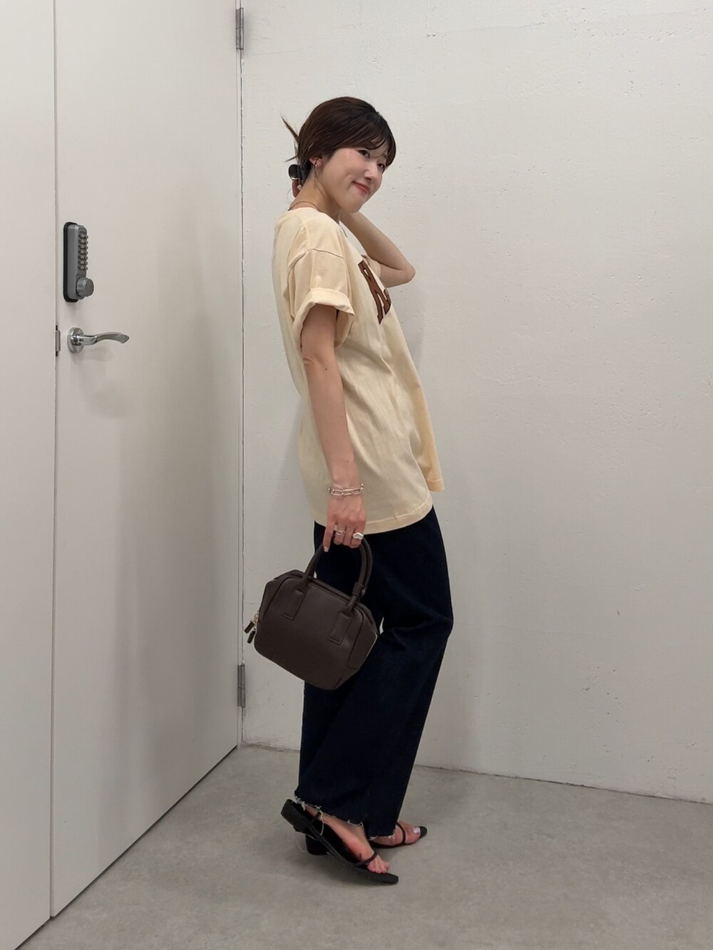 ベージュ系のTシャツ/カットソー、ブルー系のデニムパンツ、ブラウン系のショルダーバッグを着用したレディースの夏コーディネートの2枚目の写真