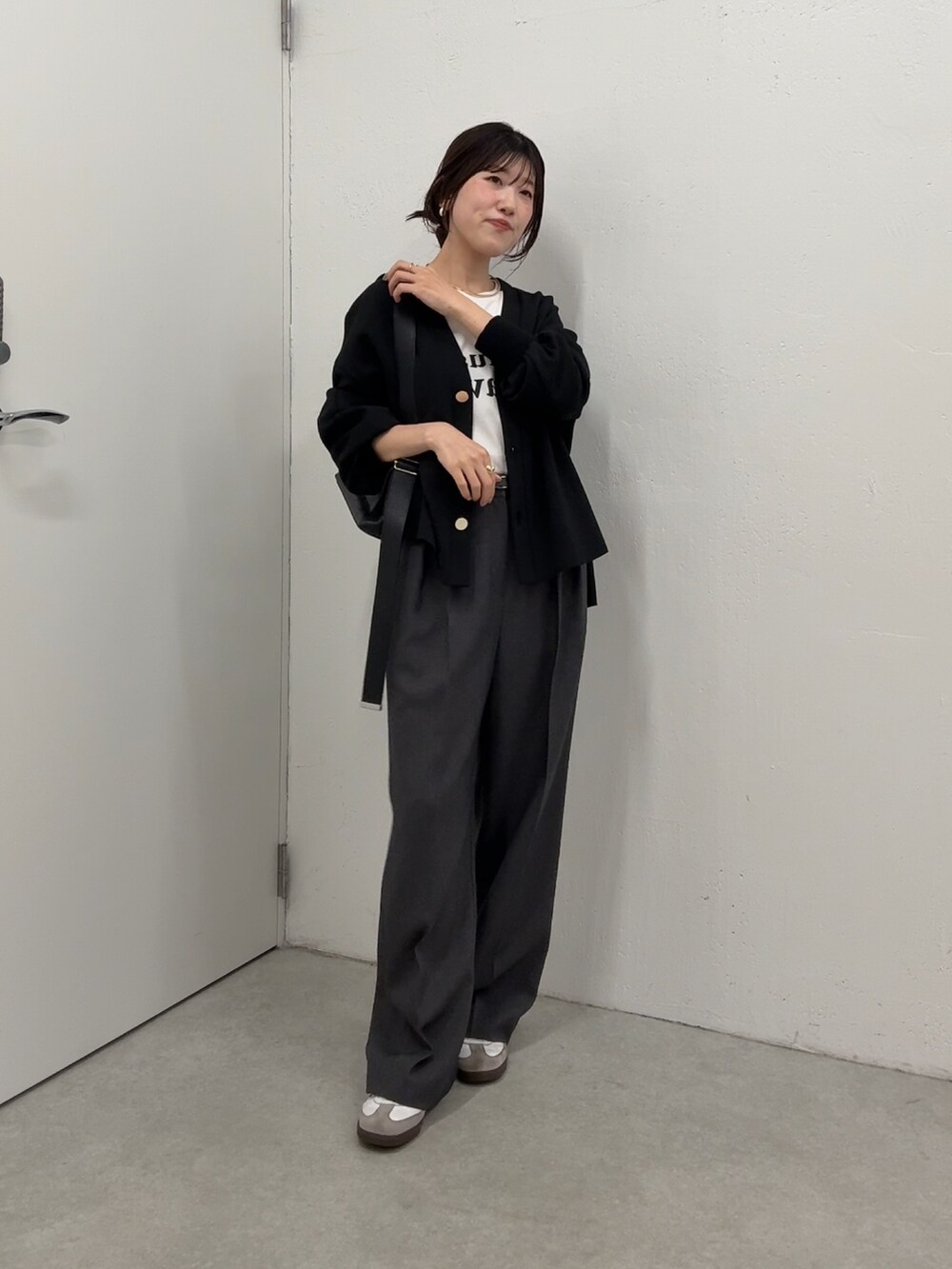 ブラック系のカーディガン/ボレロ、ホワイト系のTシャツ/カットソー、グレー系のスラックスを着用したレディースの秋コーディネートの2枚目の写真