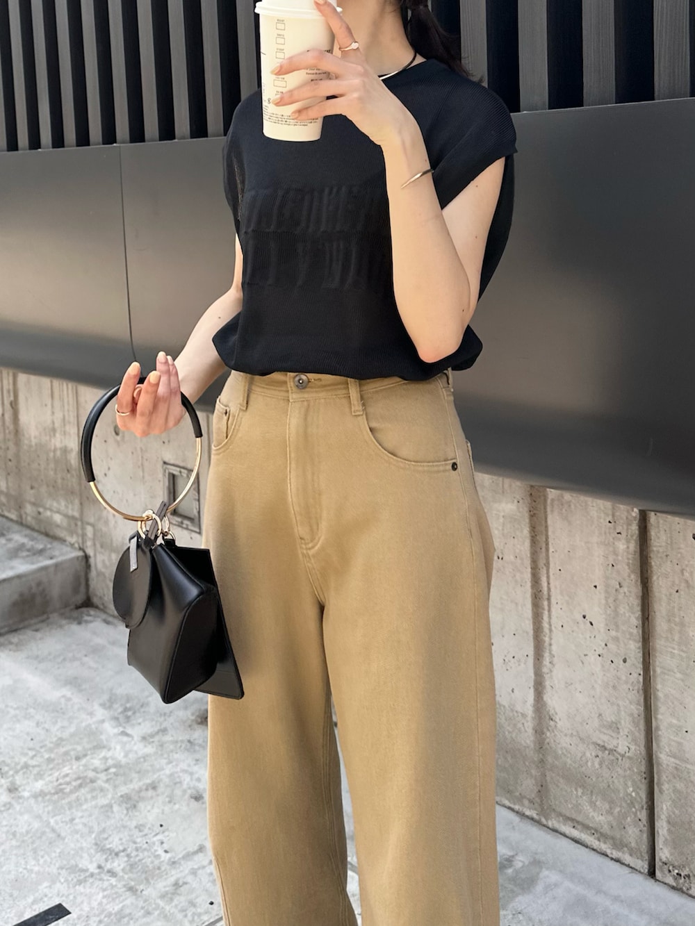 ブラック系のニット/セーター、ホワイト系のバッグ、ベージュ系のデニムパンツを着用したレディースの春コーディネートの3枚目の写真