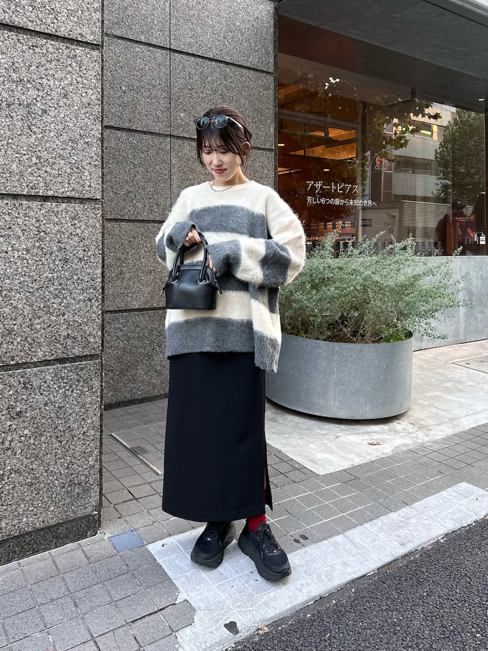 グレー系のニット/セーター、ブラック系のスカート、ブラック系のバッグを着用したレディースの秋コーディネートの3枚目の写真