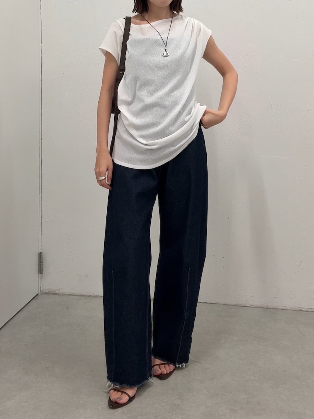 ホワイト系のTシャツ/カットソー、ブルー系のデニムパンツ、ブラック系のショルダーバッグを着用したレディースの春コーディネートの4枚目の写真