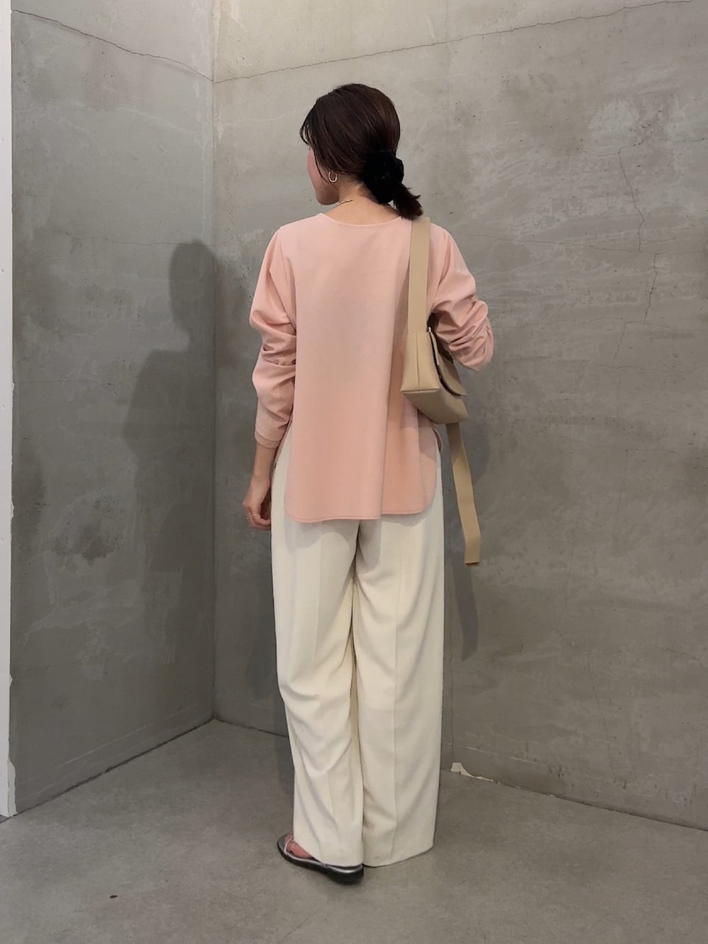 ピンク系のTシャツ/カットソー、ホワイト系のスラックス、ベージュ系のショルダーバッグを着用したレディースの冬コーディネートの3枚目の写真