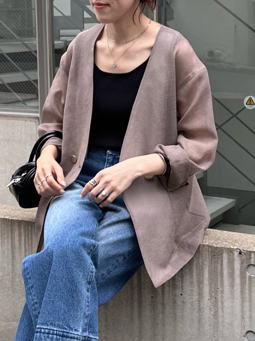 ブラック系のバッグ、ブラウン系のノーカラージャケット、ブルー系のデニムパンツを着用したレディースの夏コーディネートの2枚目の写真