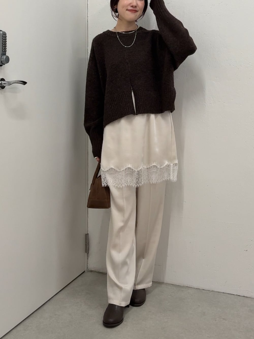 ブラウン系のニット/セーター、ホワイト系のその他パンツ、ブラウン系のボストンバッグを着用したレディースの秋コーディネートの4枚目の写真