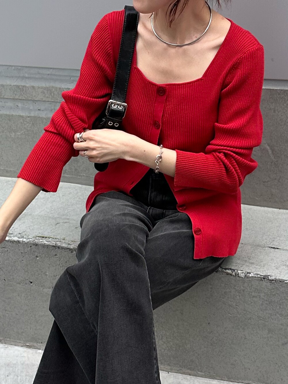 レッド系のニット/セーター、ブラック系のデニムパンツ、ブラック系のバッグを着用したレディースの夏コーディネートの4枚目の写真