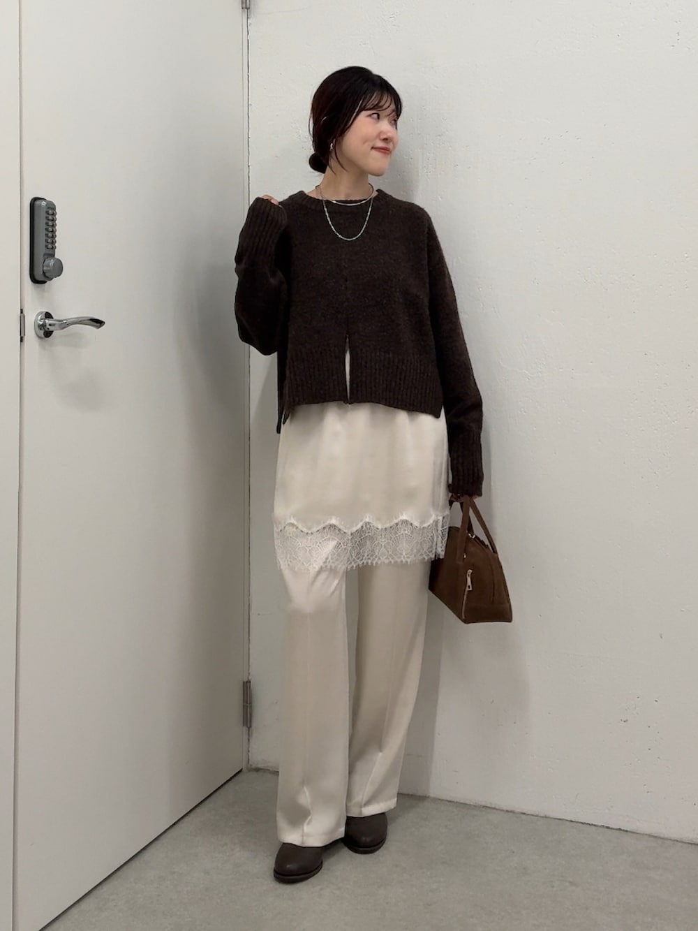 ブラウン系のニット/セーター、ホワイト系のその他パンツ、ブラウン系のボストンバッグを着用したレディースの秋コーディネートの5枚目の写真