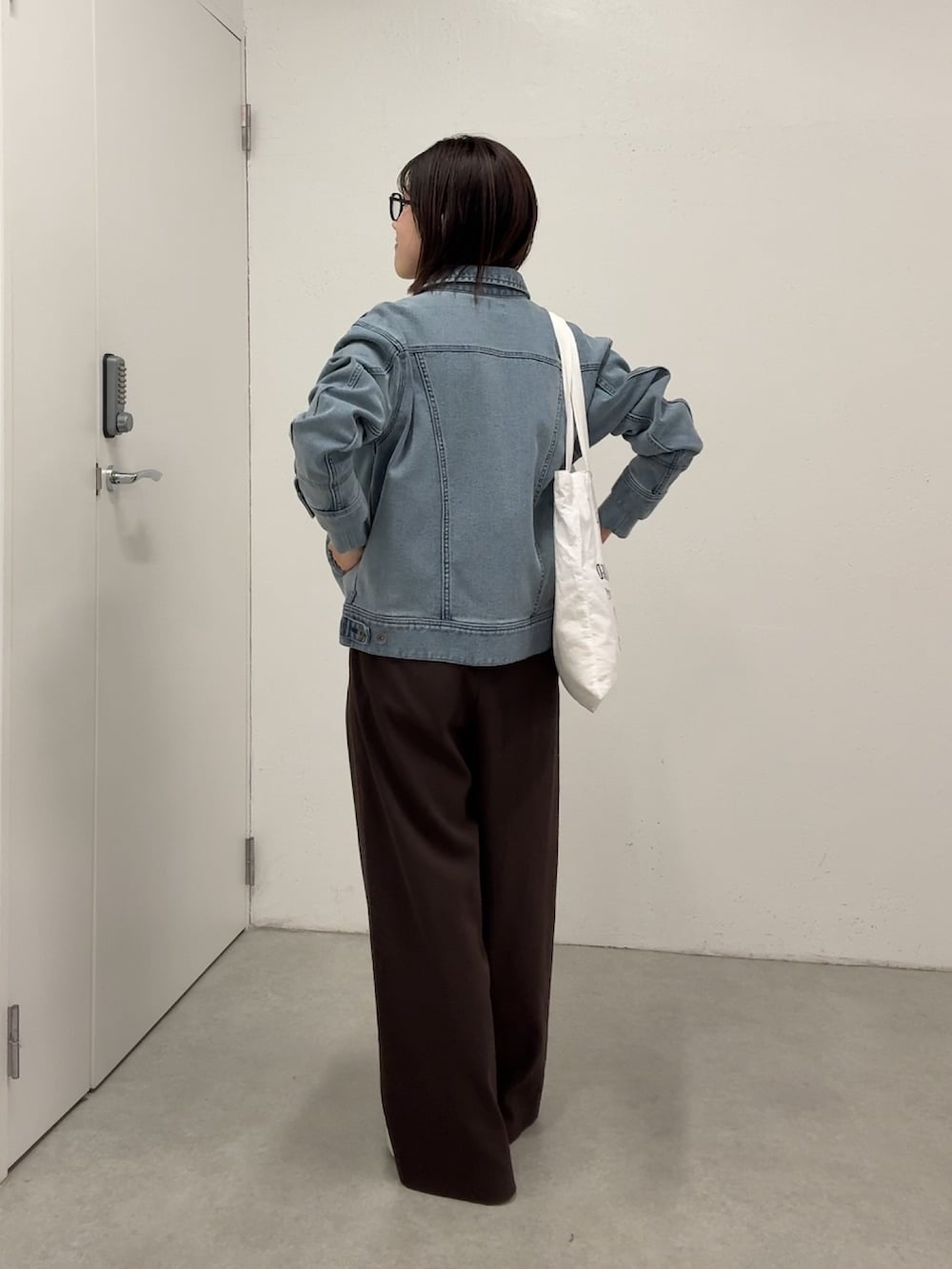 ブラウン系のスラックス、ブルー系のデニムジャケット、ブラック系のシャツ/ブラウスを着用したレディースの春コーディネートの4枚目の写真