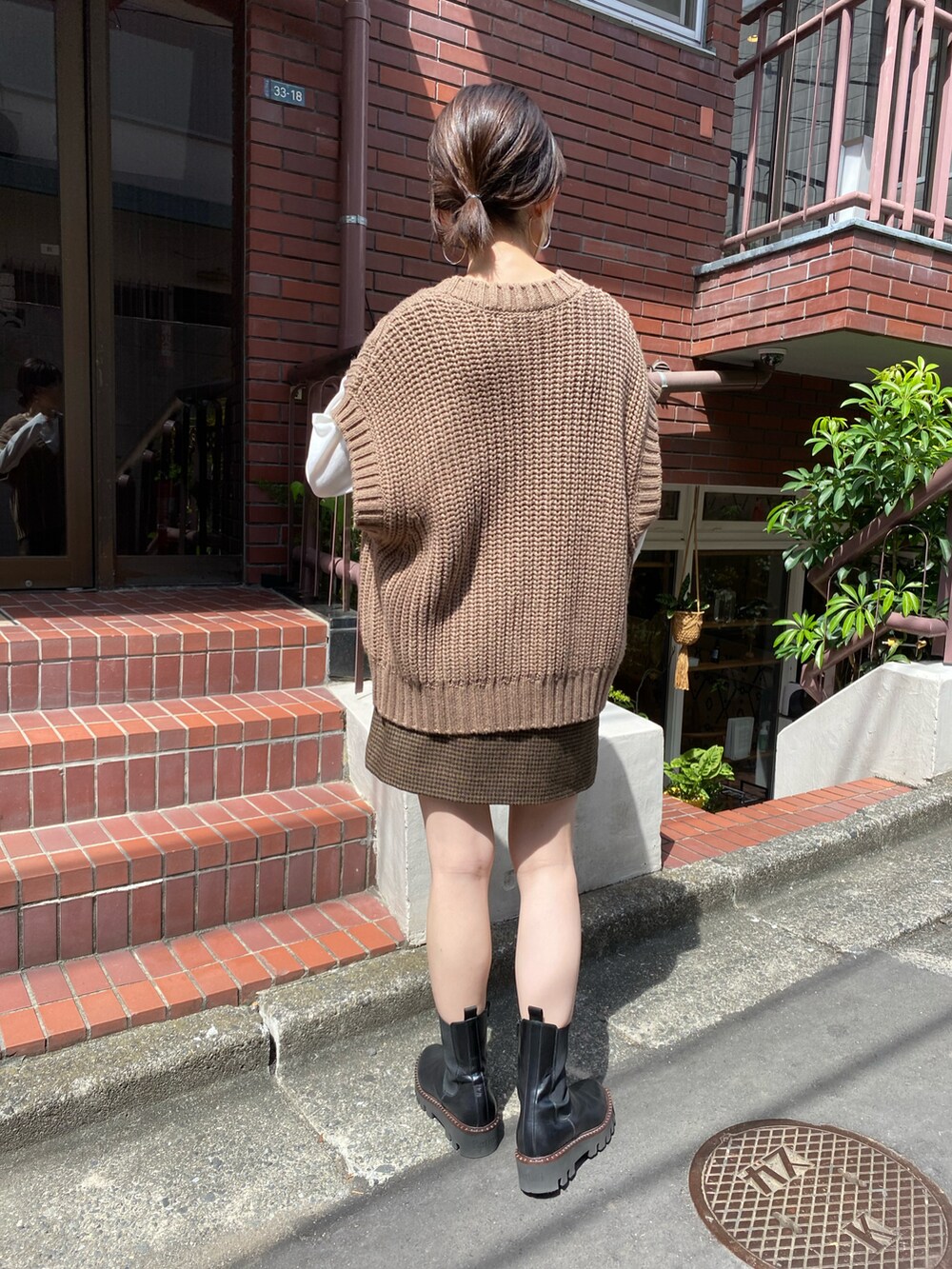 ブラウン系のベスト、ベージュ系のスカート、ブラウン系のトートバッグを着用したレディースの秋コーディネートの4枚目の写真