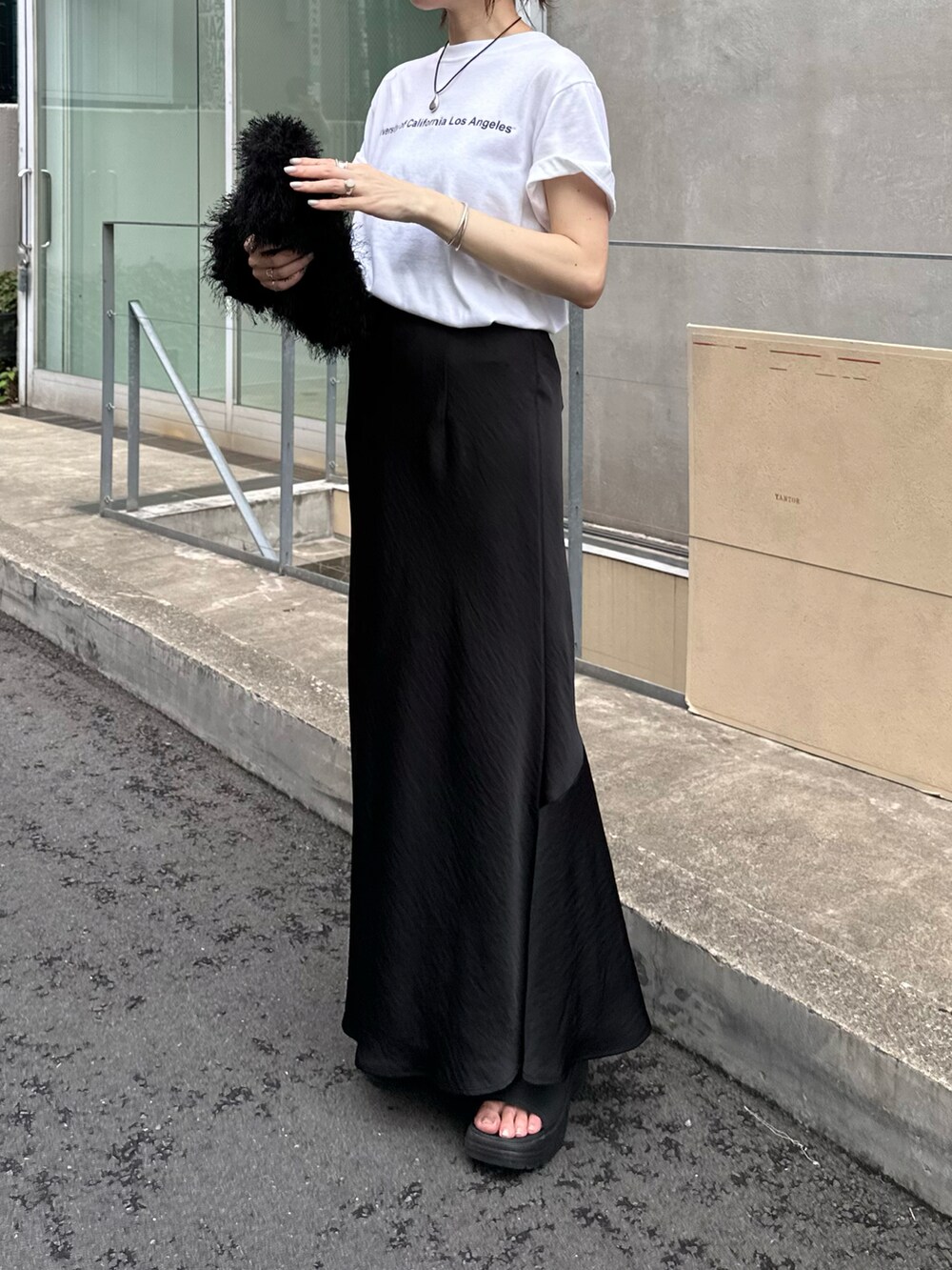 ホワイト系のTシャツ/カットソー、ブラック系のバッグ、ブラック系のスカートを着用したレディースの夏コーディネートの3枚目の写真