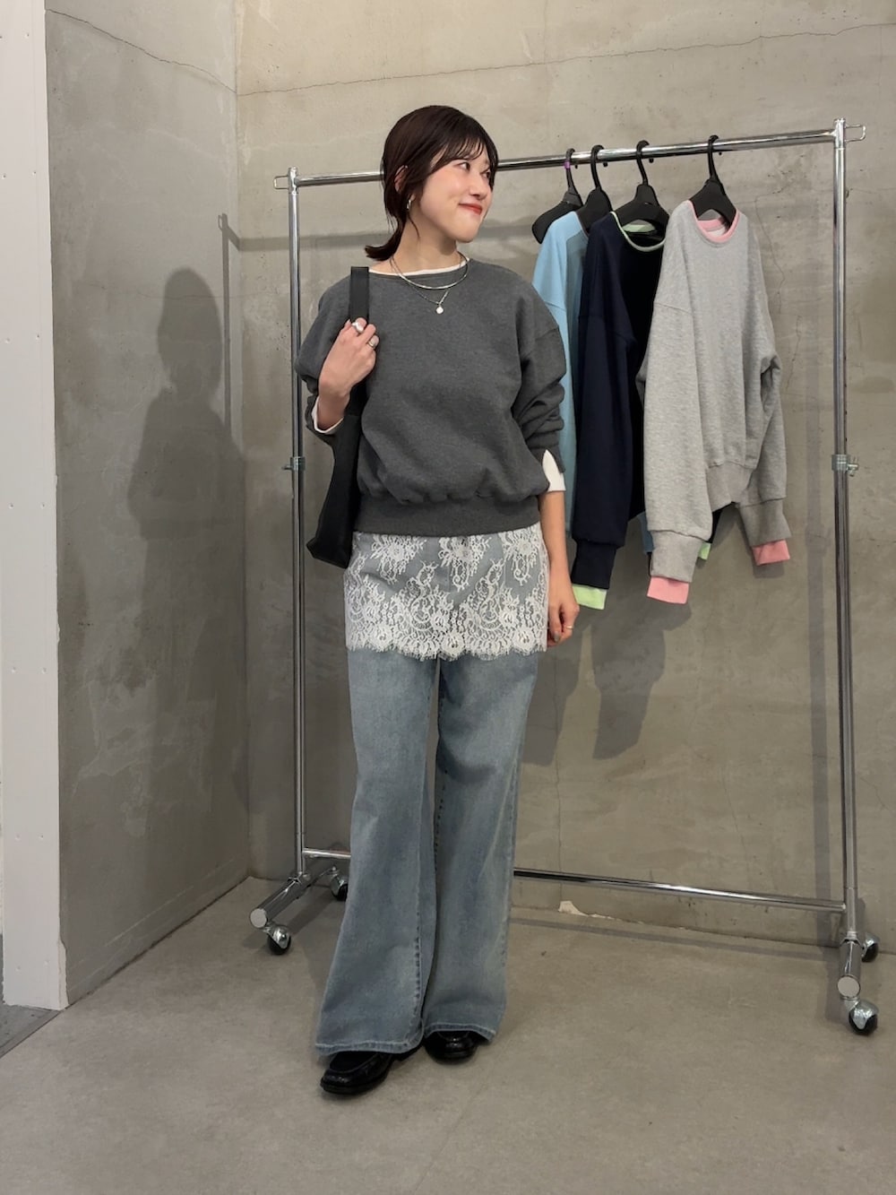 グレー系のスウェット、ホワイト系のスカート、ブルー系のデニムパンツを着用したレディースの春コーディネートの4枚目の写真