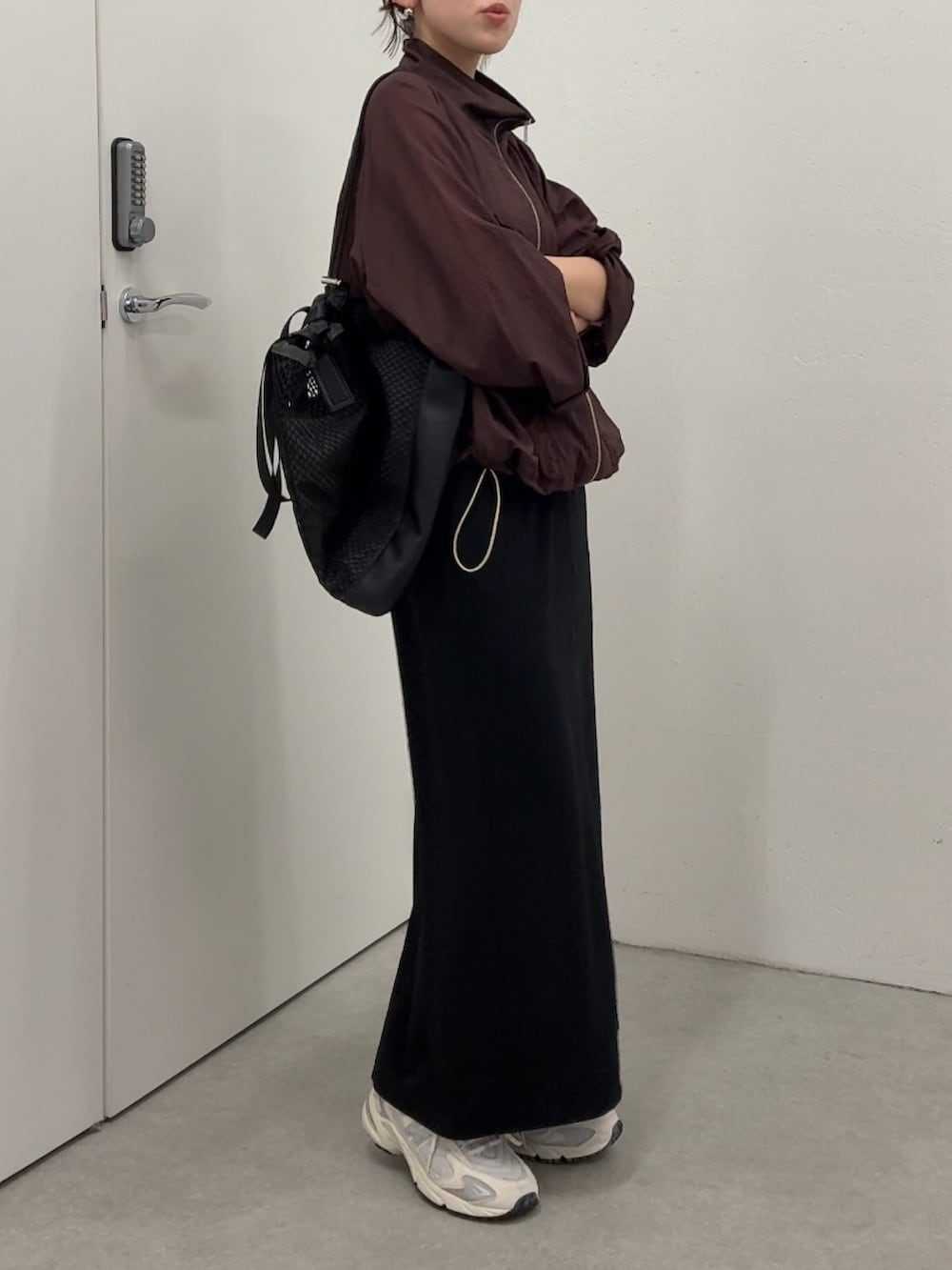 ブラウン系のマウンテンパーカー、ブラック系のスカート、ブラック系のトートバッグを着用したレディースの春コーディネートの5枚目の写真