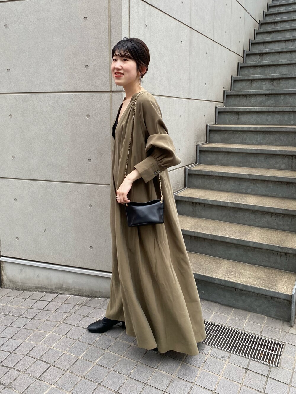 グリーン系のワンピース、ブラック系のブーツ、ブラック系のトートバッグを着用したレディースの夏コーディネートの2枚目の写真