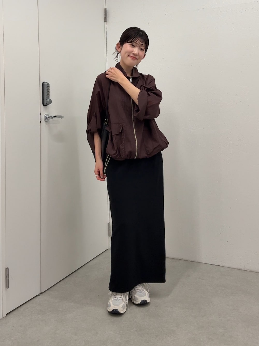 ブラウン系のマウンテンパーカー、ブラック系のスカート、ブラック系のトートバッグを着用したレディースの春コーディネートの3枚目の写真