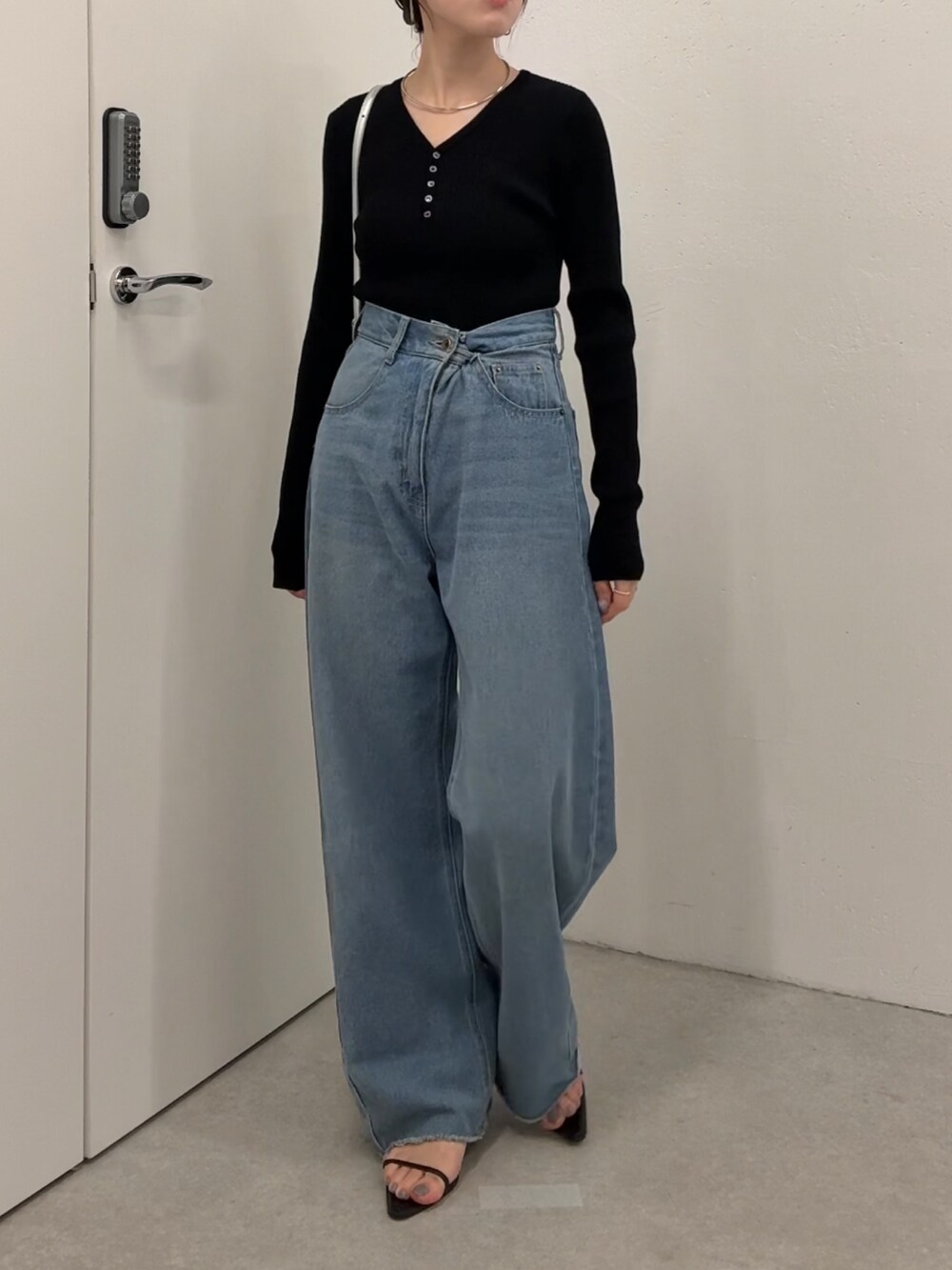 ブラック系のニット/セーター、ブルー系のデニムパンツ、シルバー系のショルダーバッグを着用したレディースの夏コーディネートの4枚目の写真