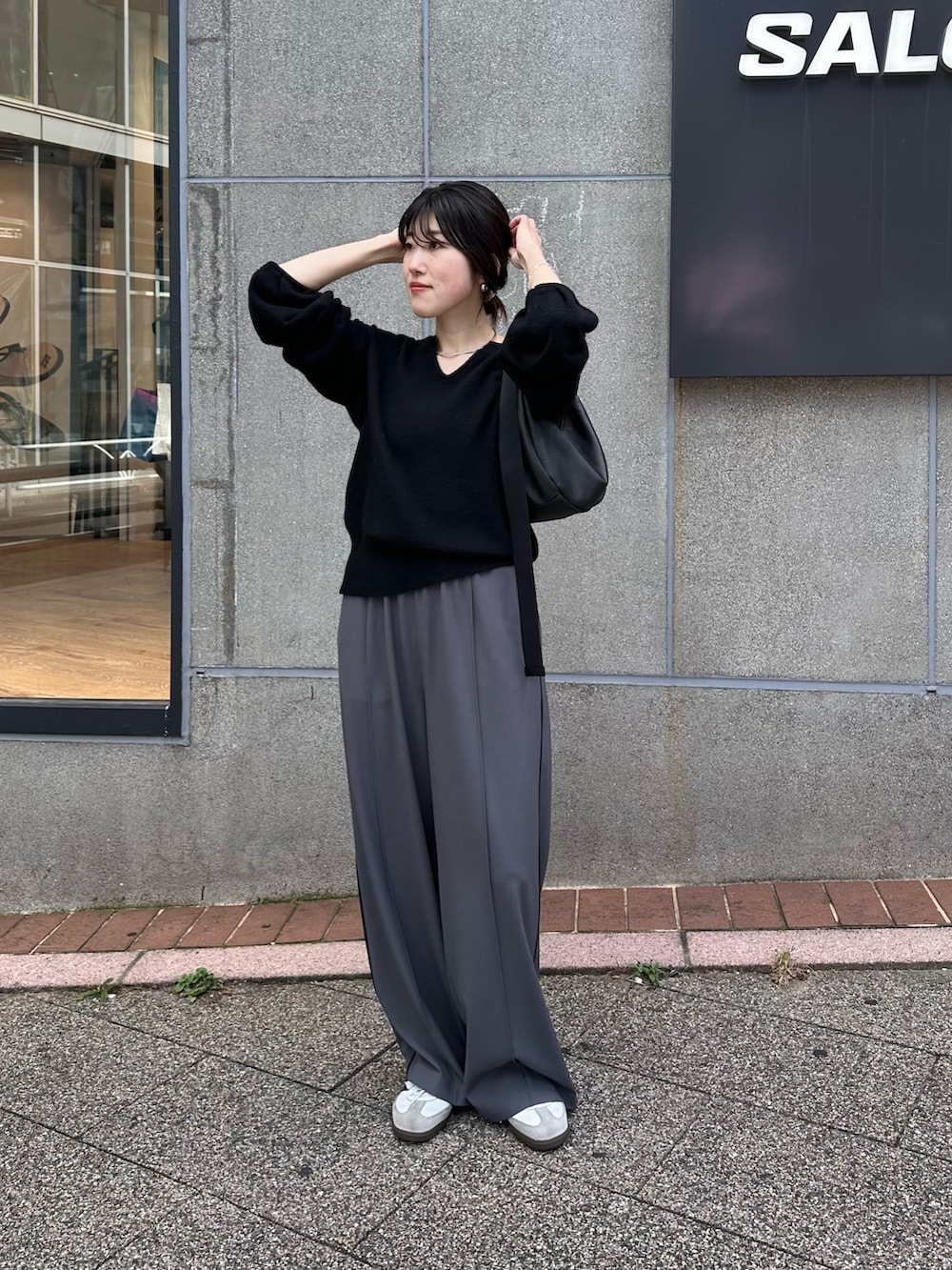 ブラック系のニット/セーター、ブルー系のスラックスを着用したレディースの秋コーディネートの5枚目の写真