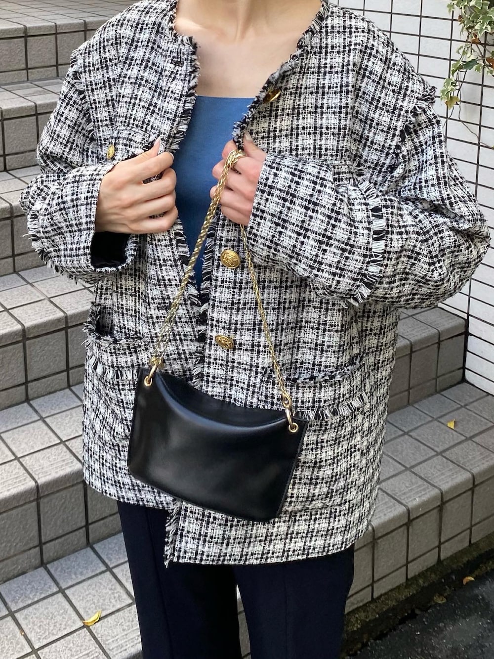 ブルー系のスラックス、ブラック系のノーカラージャケット、ブルー系のタンクトップを着用したレディースの秋コーディネートの2枚目の写真