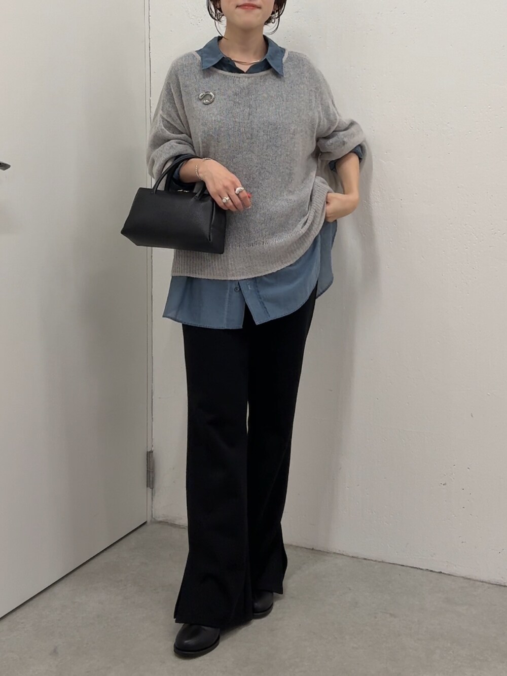 グレー系のニット/セーター、ブルー系のシャツ/ブラウス、ブラック系のボストンバッグを着用したレディースの秋コーディネートの4枚目の写真