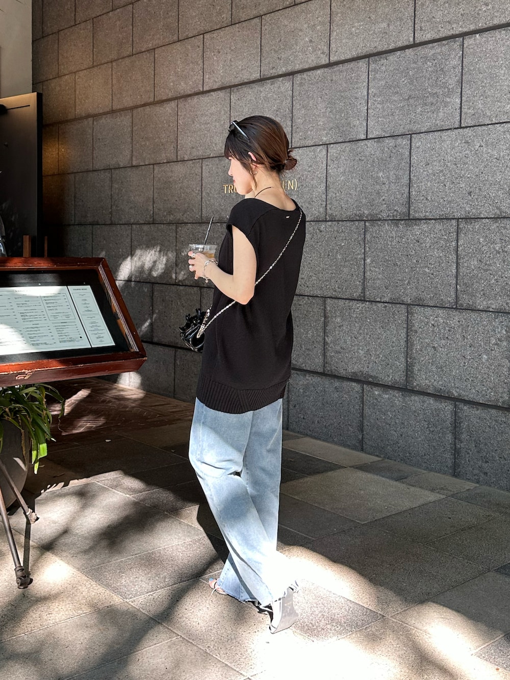 ブラック系のニット/セーター、ブルー系のデニムパンツ、ブラック系のシューズを着用したレディースの春コーディネートの3枚目の写真