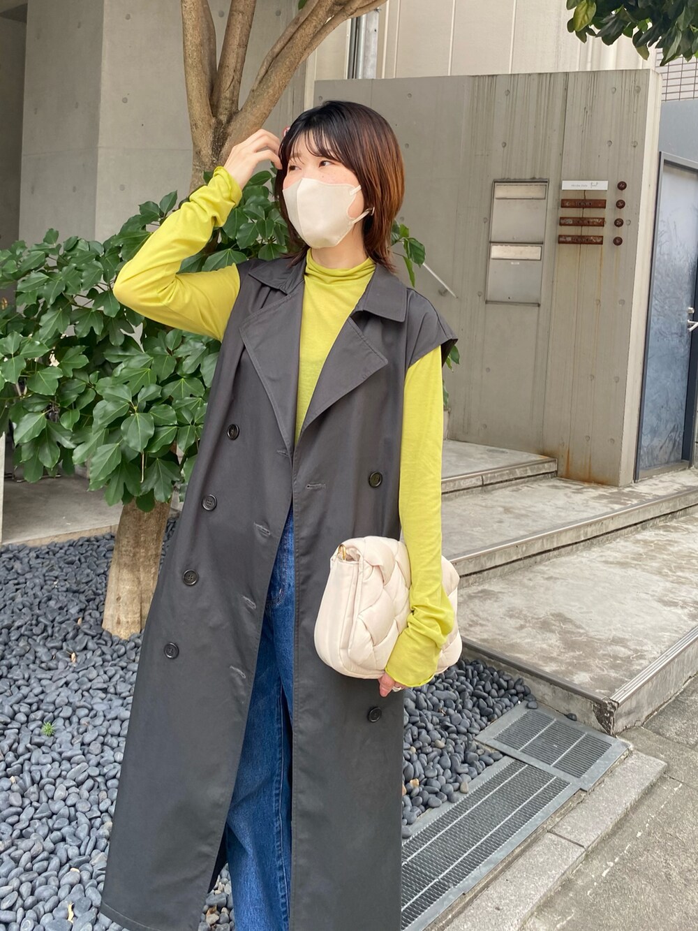 グレー系のトレンチコート、グリーン系のTシャツ/カットソー、ホワイト系のショルダーバッグを着用したレディースの夏コーディネートの3枚目の写真