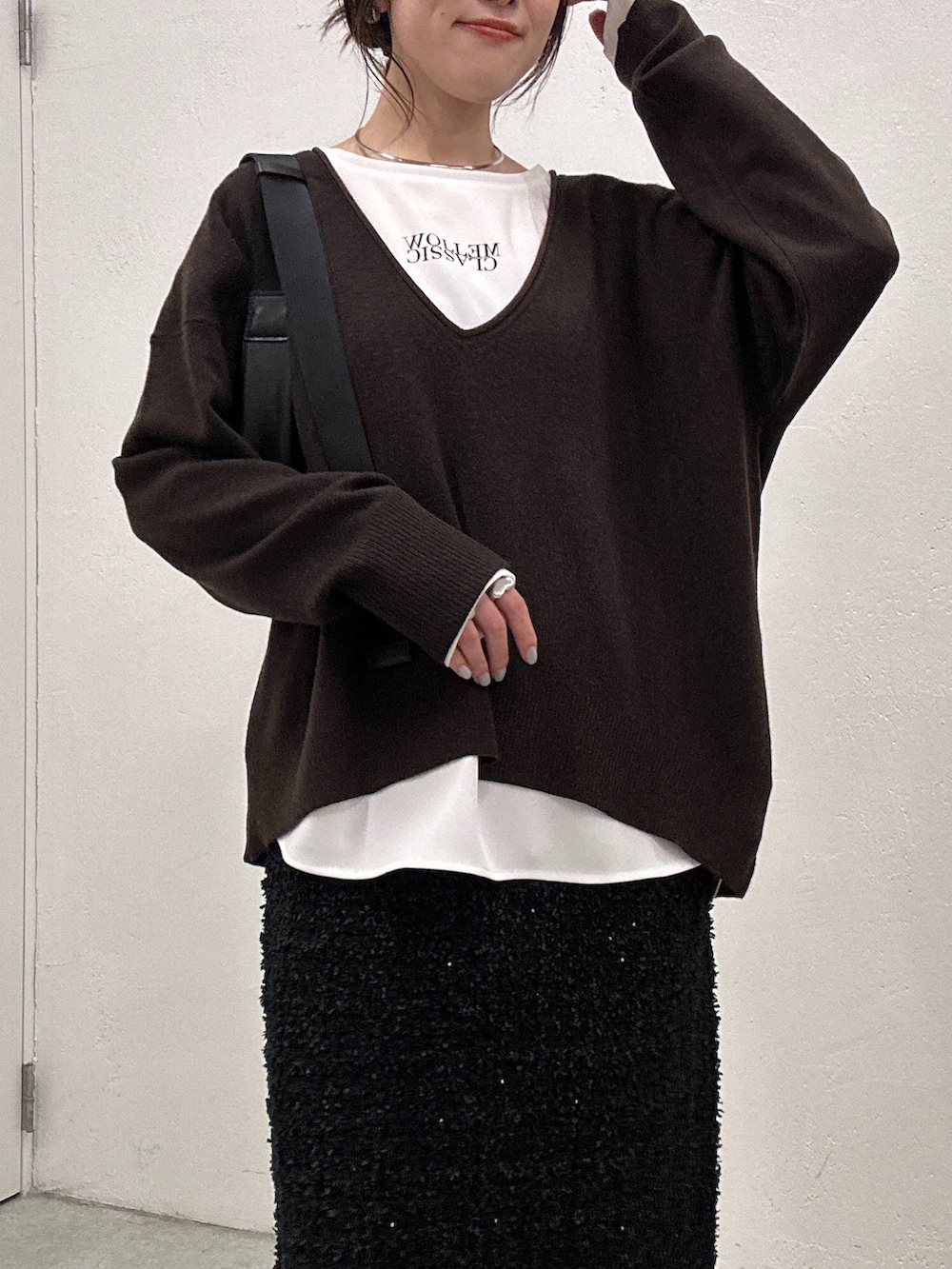 ブラウン系のニット/セーター、ブラック系のスカート、ホワイト系のシャツ/ブラウスを着用したレディースの秋コーディネートの2枚目の写真