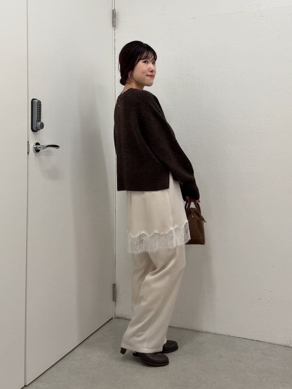 ブラウン系のニット/セーター、ホワイト系のその他パンツ、ブラウン系のボストンバッグを着用したレディースの秋コーディネートの3枚目の写真