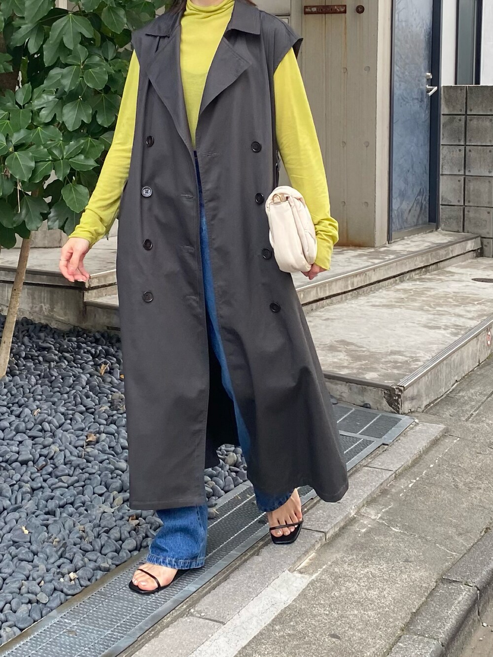 グレー系のトレンチコート、グリーン系のTシャツ/カットソー、ホワイト系のショルダーバッグを着用したレディースの夏コーディネートの2枚目の写真