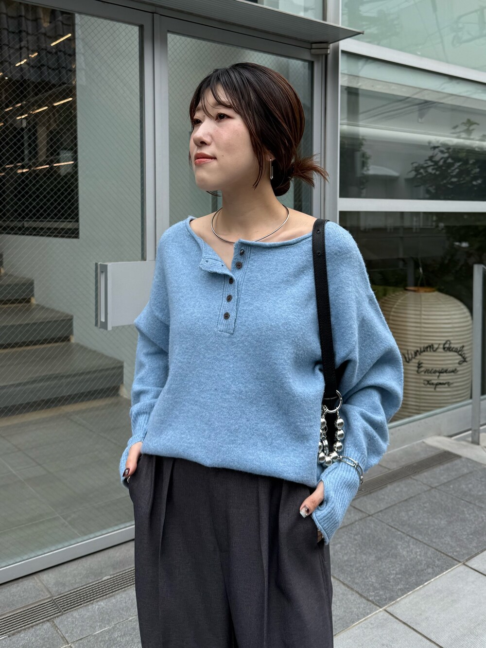 ブルー系のニット/セーター、グレー系のスラックスを着用したレディースの秋コーディネートの3枚目の写真