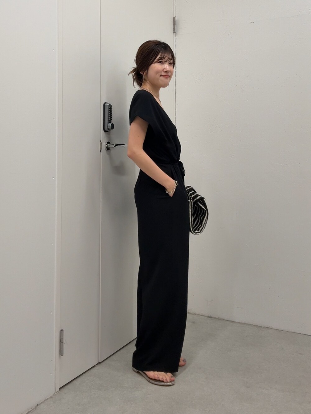 ブラック系のつなぎ/オールインワン、ブラック系のトートバッグ、ゴールド系のネックレスを着用したレディースの春コーディネートの2枚目の写真