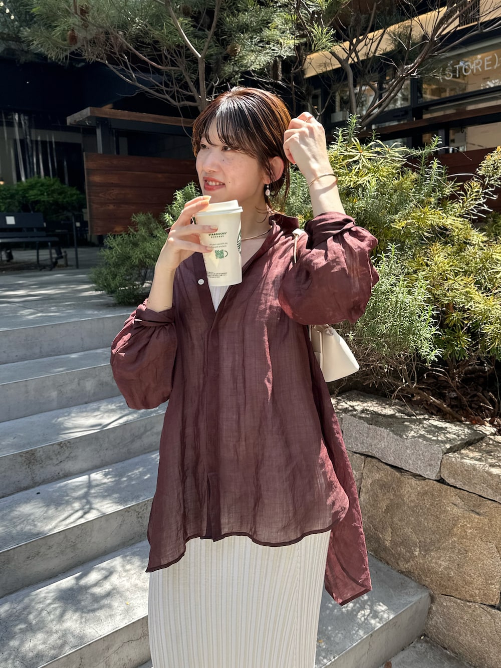 ブラウン系のシャツ/ブラウス、ホワイト系のワンピースを着用したレディースの春コーディネートの2枚目の写真