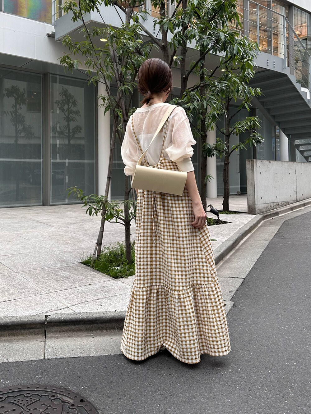 ベージュ系のワンピース、ホワイト系のTシャツ/カットソー、ブラック系のシューズを着用したレディースの春コーディネートの2枚目の写真