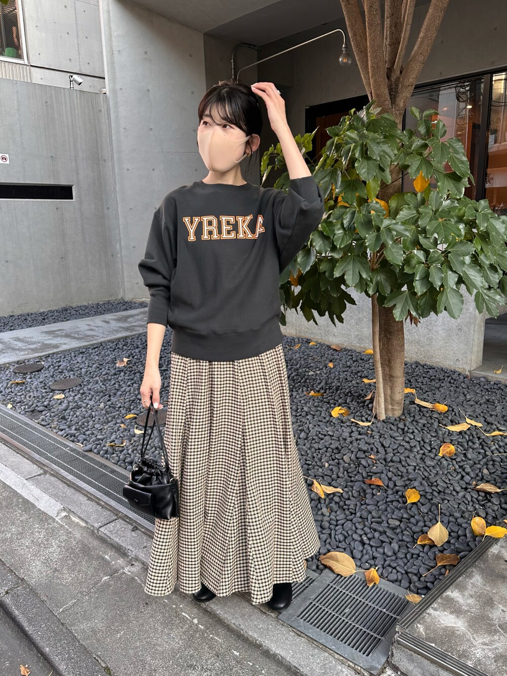 グレー系のスウェット、ベージュ系のスカート、ブラック系のショルダーバッグを着用したレディースの秋コーディネートの4枚目の写真