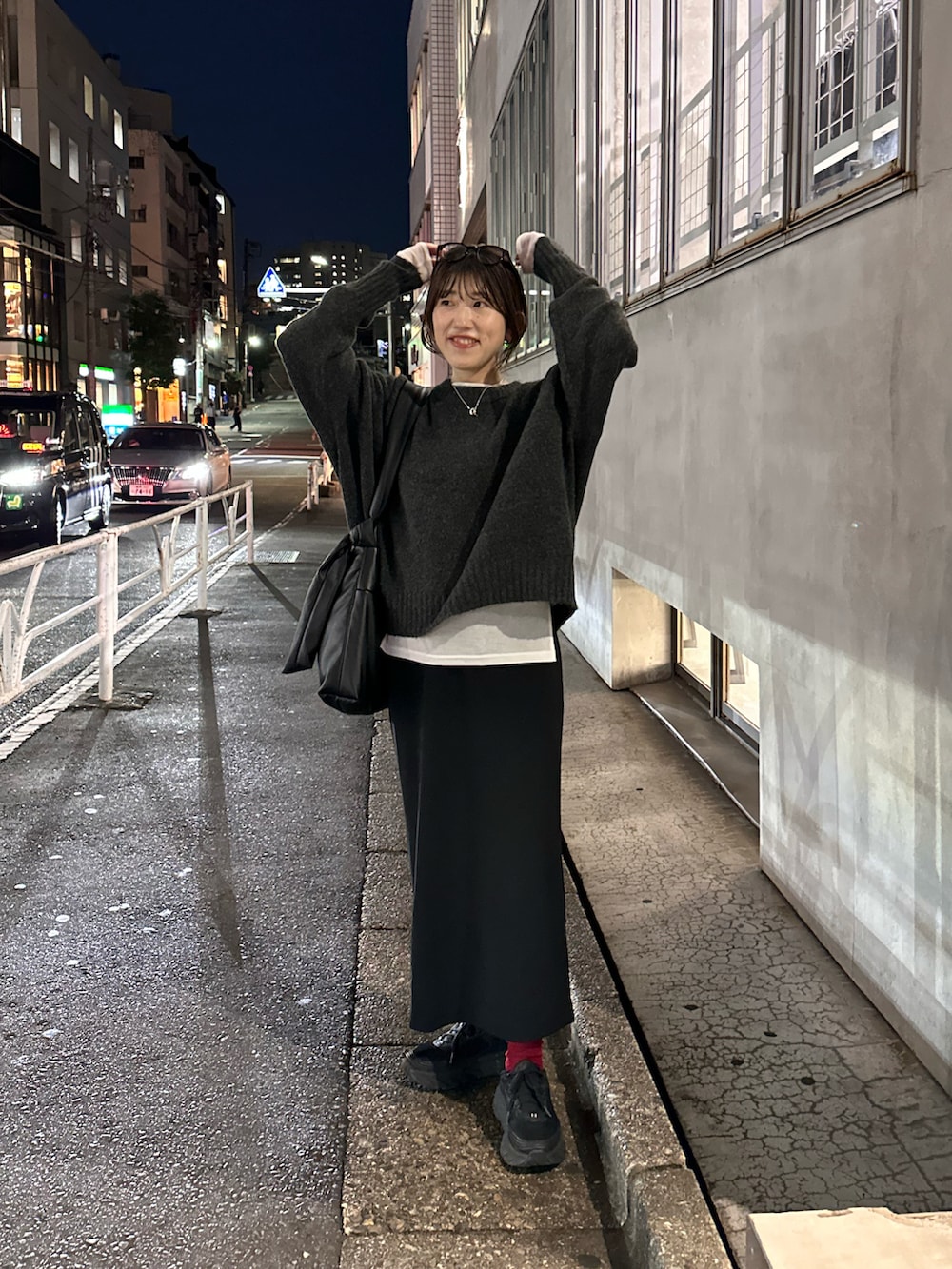 グレー系のニット/セーター、ブラック系のスカート、ホワイト系のTシャツ/カットソーを着用したレディースの秋コーディネートの4枚目の写真