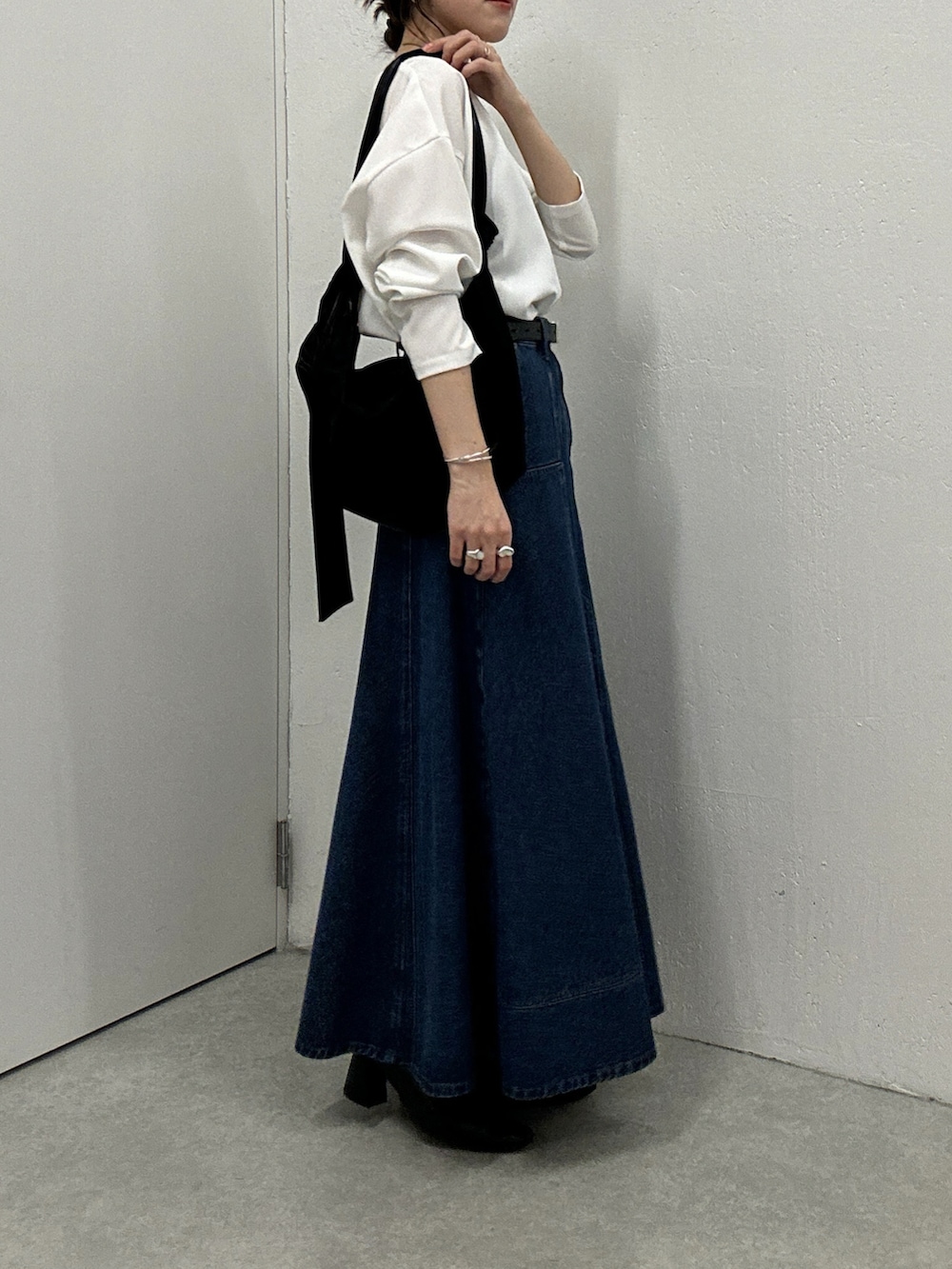 ブルー系のスカート、ホワイト系のシャツ/ブラウス、ブラック系のショルダーバッグを着用したレディースの秋コーディネートの3枚目の写真