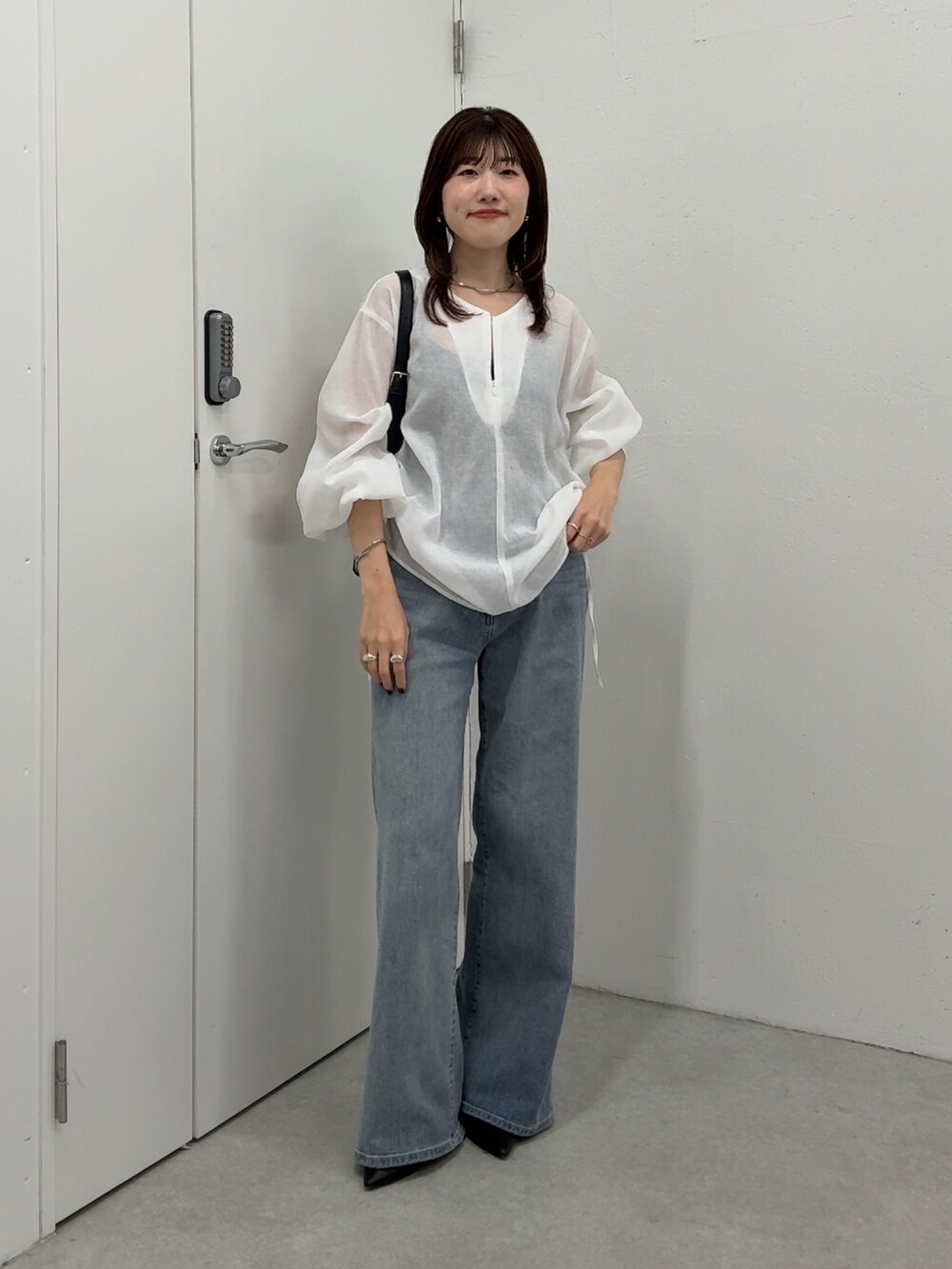 ホワイト系のシャツ/ブラウス、ブルー系のデニムパンツ、ブラック系のショルダーバッグを着用したレディースの春コーディネートの4枚目の写真