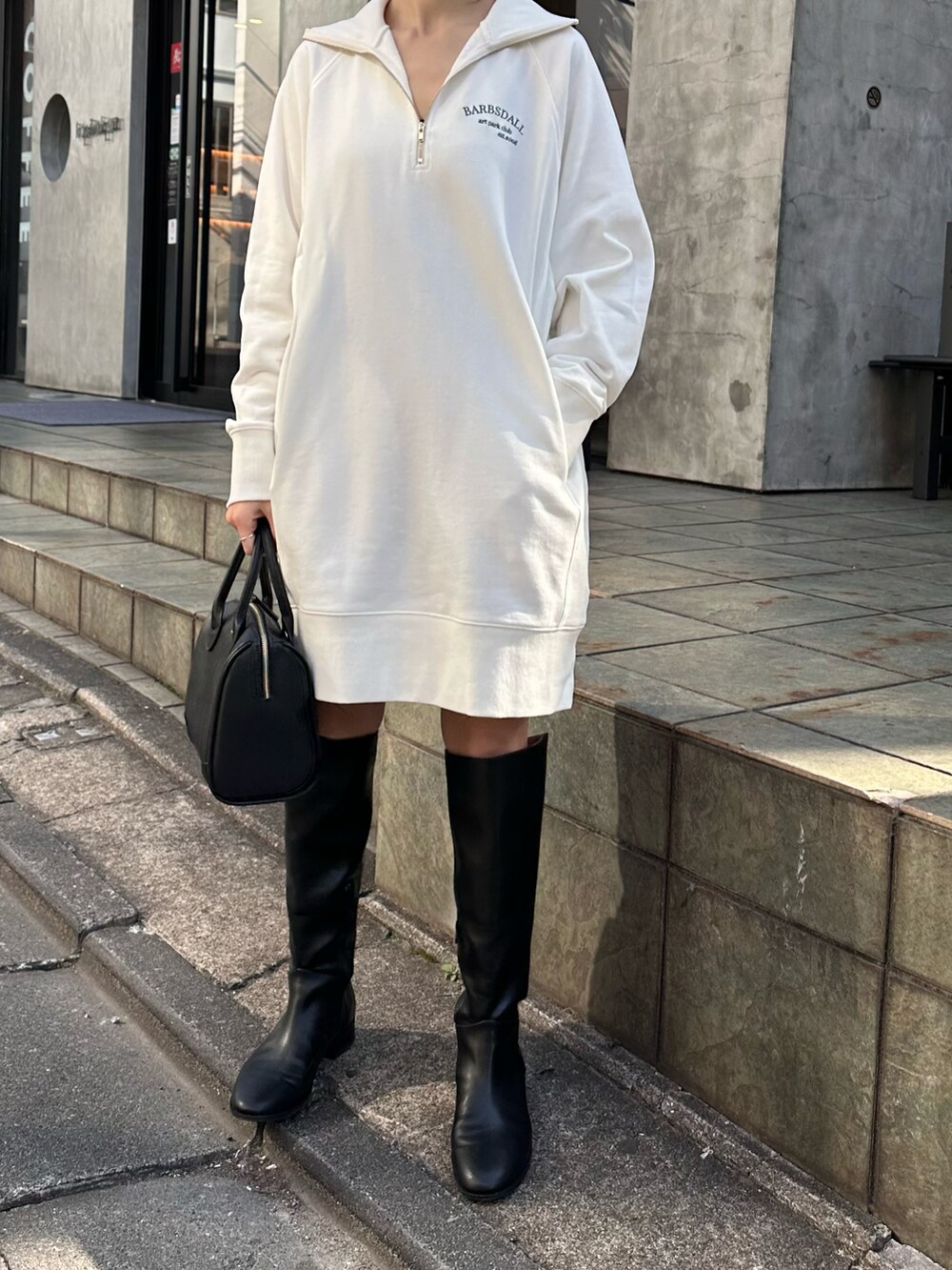 ホワイト系のスウェット、ブラック系のボストンバッグ、ブラック系のブーツを着用したレディースの秋コーディネートの2枚目の写真