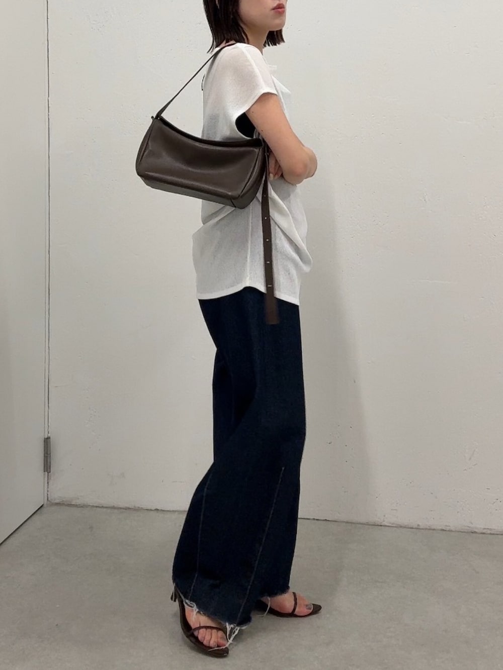 ホワイト系のTシャツ/カットソー、ブルー系のデニムパンツ、ブラック系のショルダーバッグを着用したレディースの春コーディネートの2枚目の写真