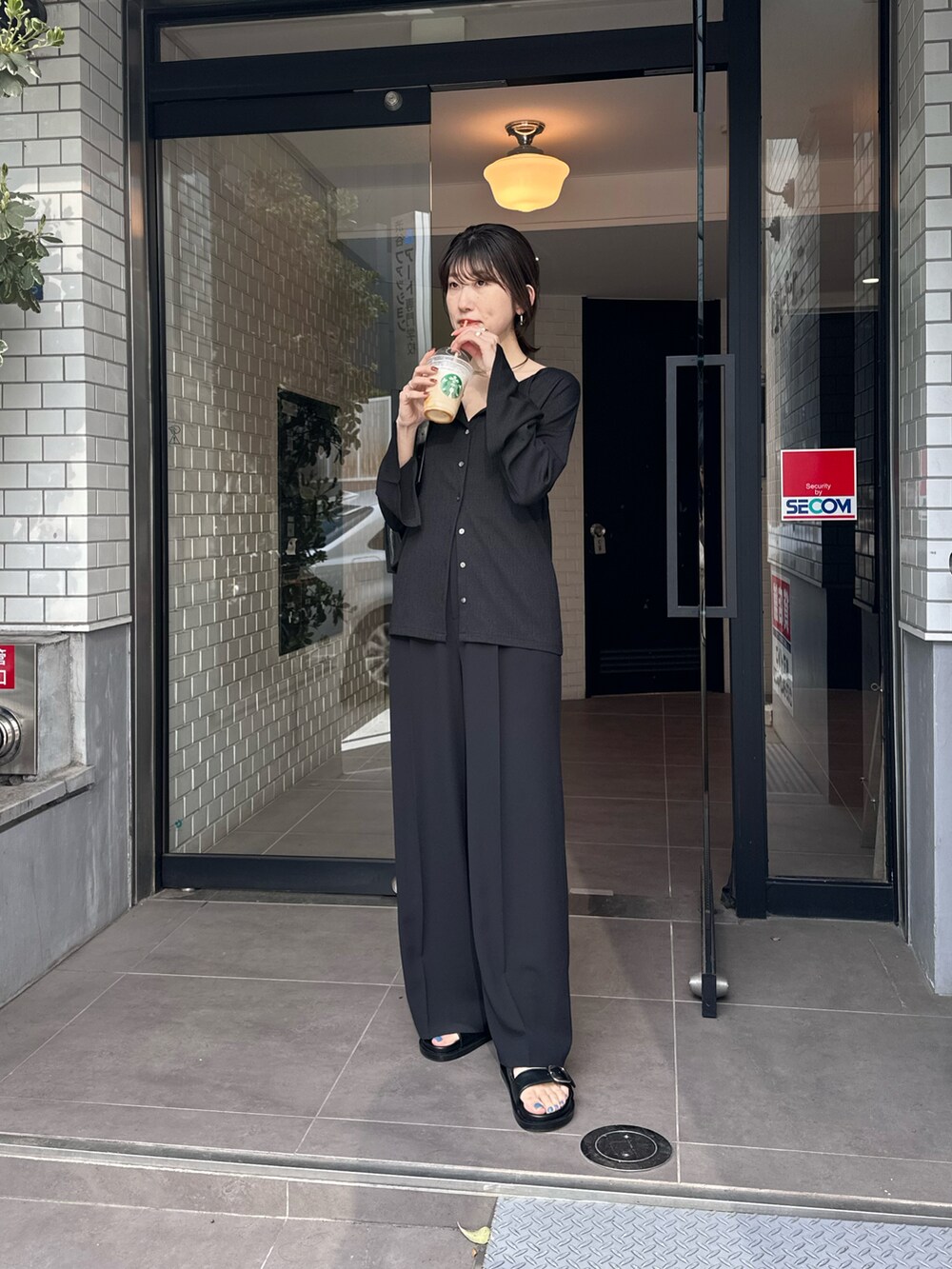 ブラック系のシャツ/ブラウス、ブラック系のスラックス、ブラック系のサンダルを着用したレディースの春コーディネートの3枚目の写真