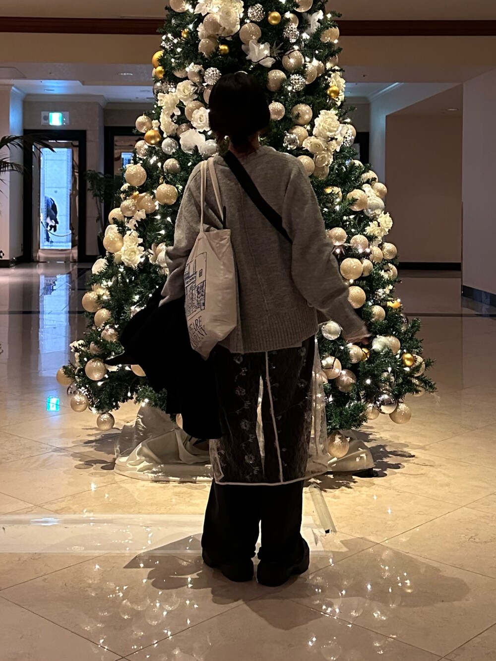 グレー系のニット/セーター、ホワイト系のワンピース、ブルー系のデニムパンツを着用したレディースの冬コーディネートの2枚目の写真