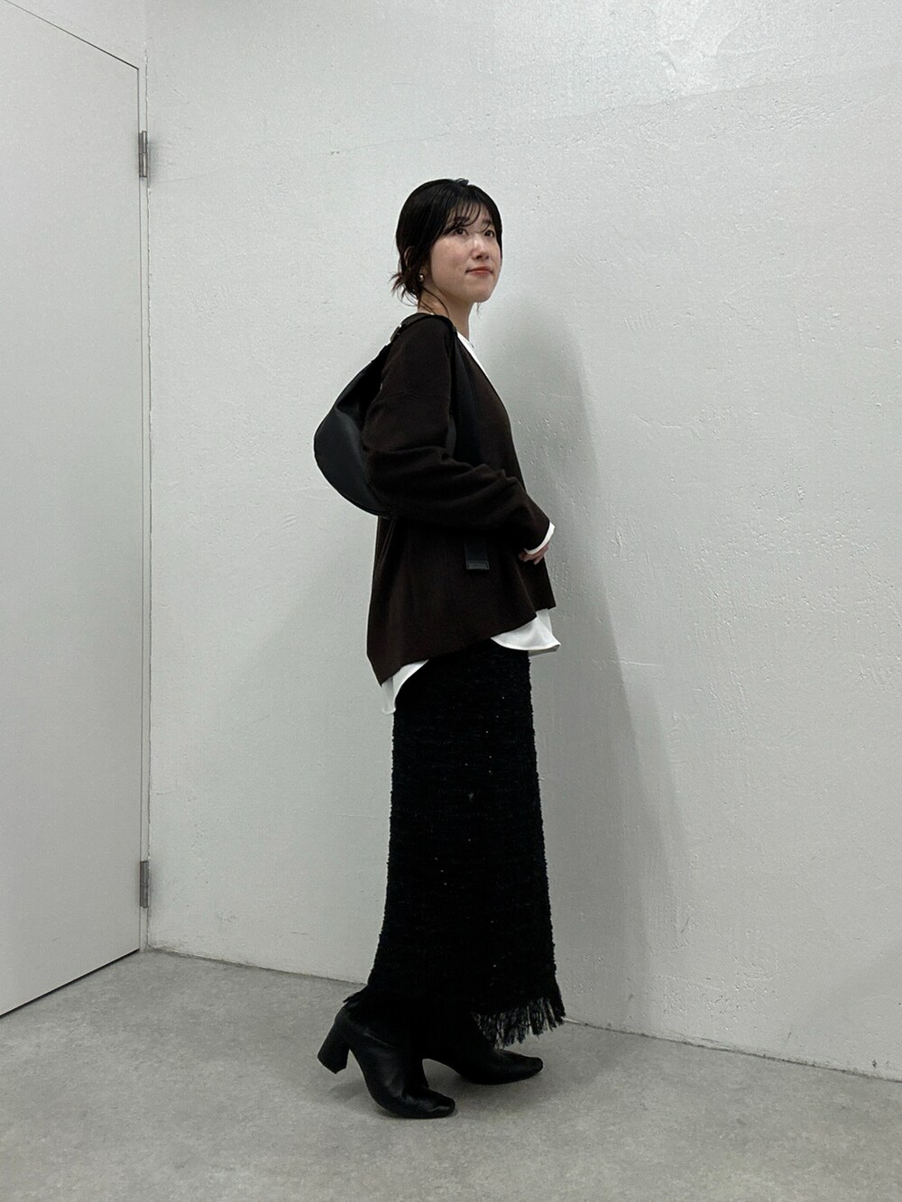 ブラウン系のニット/セーター、ブラック系のスカート、ホワイト系のシャツ/ブラウスを着用したレディースの秋コーディネートの4枚目の写真