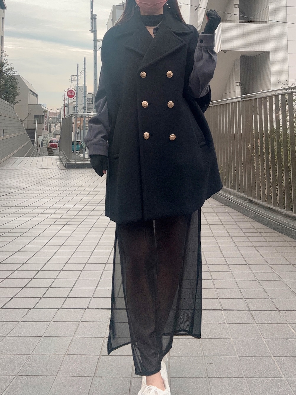 ブラック系のスカート、ホワイト系のスニーカー、ブラック系のポンチョを着用したレディースの冬コーディネートの3枚目の写真