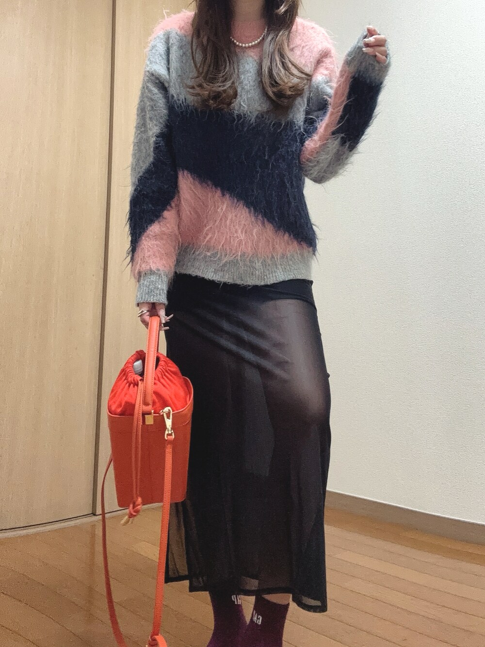 ピンク系のニット/セーター、オレンジ系のショルダーバッグ、ブラック系のスカートを着用したレディースの秋コーディネートの3枚目の写真