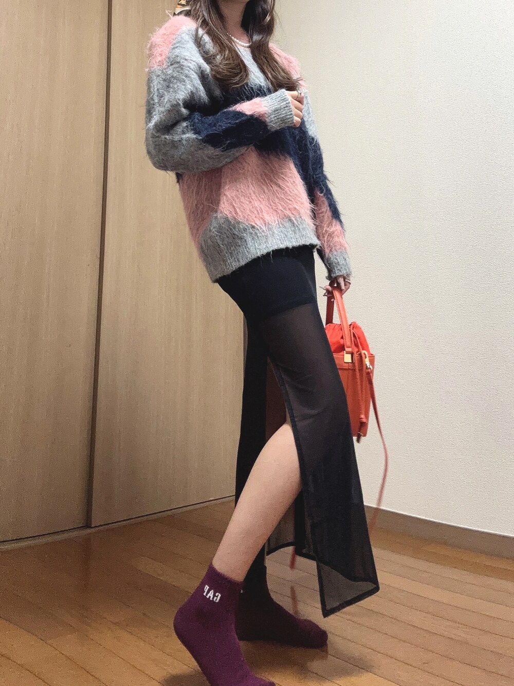 ピンク系のニット/セーター、オレンジ系のショルダーバッグ、ブラック系のスカートを着用したレディースの秋コーディネートの5枚目の写真