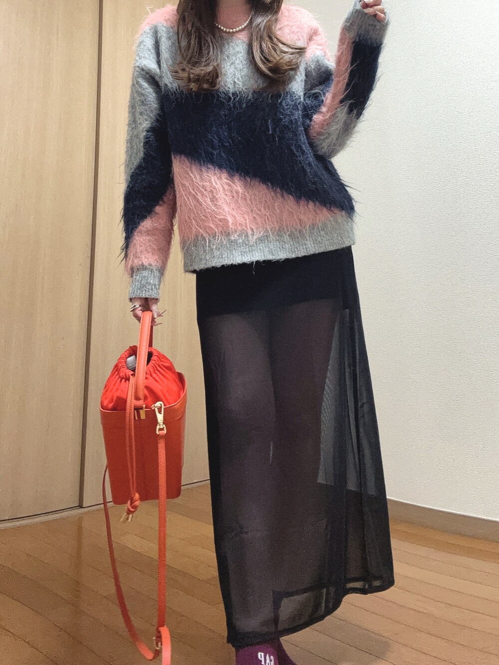 ピンク系のニット/セーター、オレンジ系のショルダーバッグ、ブラック系のスカートを着用したレディースの秋コーディネートの2枚目の写真