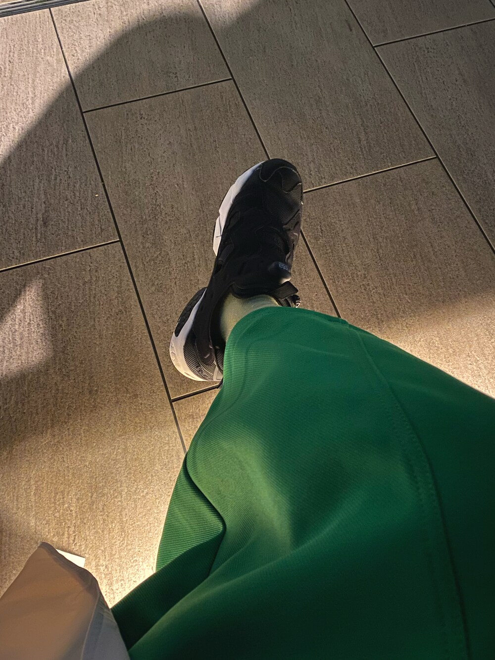 ホワイト系のトレンチコート、グリーン系のスカート、ブルー系のキャップを着用したレディースの春コーディネートの2枚目の写真